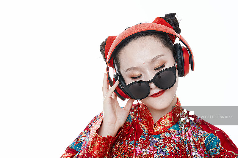 白色背景下穿着秀禾服听音乐玩手机的亚洲少女图片素材