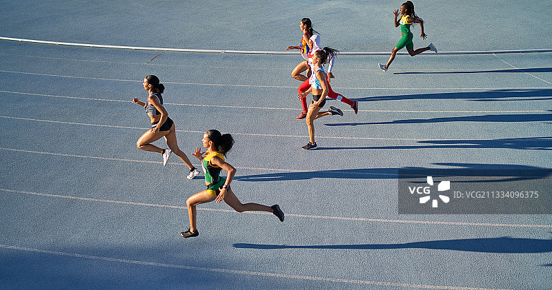女子田径运动员在蓝色的跑道上赛跑图片素材