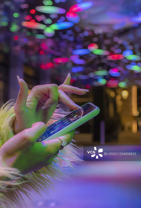 近距离女子使用智能手机在夜总会霓虹灯下图片素材
