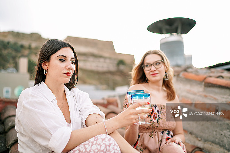 两个年轻女人在西班牙城市的屋顶上喝葡萄酒图片素材
