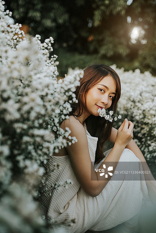 泰国清迈，一名年轻女子坐在鲜花旁的肖像图片素材