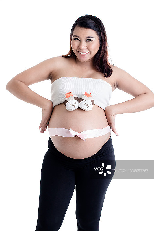 微笑孕妇的肚子与婴儿鞋和丝带蝴蝶结的白色背景图片素材