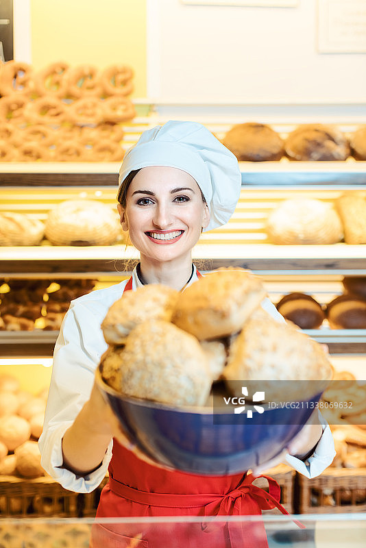 新鲜的面包卷由一个迷人的年轻女销售员在面包房图片素材