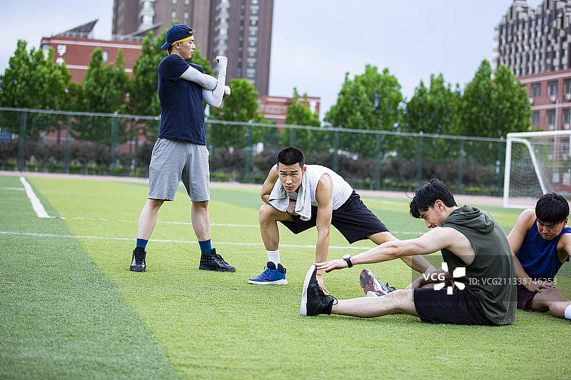 四个青年男子在学校操场做拉伸训练热身打篮球图片素材