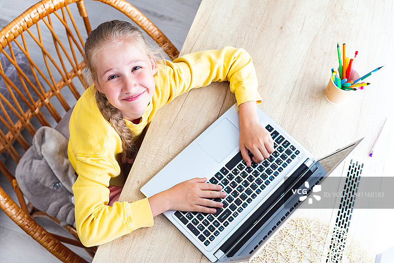 高角度肖像微笑男孩使用笔记本电脑在桌子上图片素材
