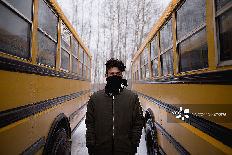 一名男子站在两辆校车之间的肖像，伦敦，安大略省，加拿大图片素材