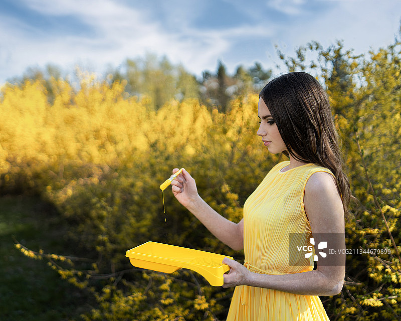 芬兰，一名年轻女子拿着黄色油漆，站在植物旁图片素材