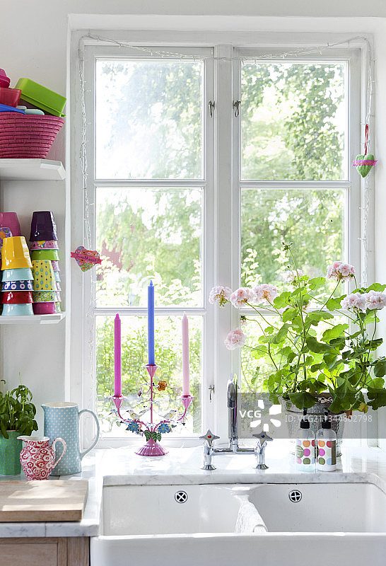 窗台上有盛开的天竺葵和烛台，前面有双水槽图片素材