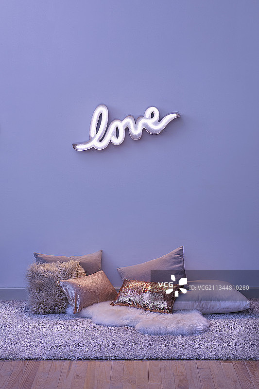 拼有“LOVE”字样的霓虹灯和地板上的各种坐垫图片素材