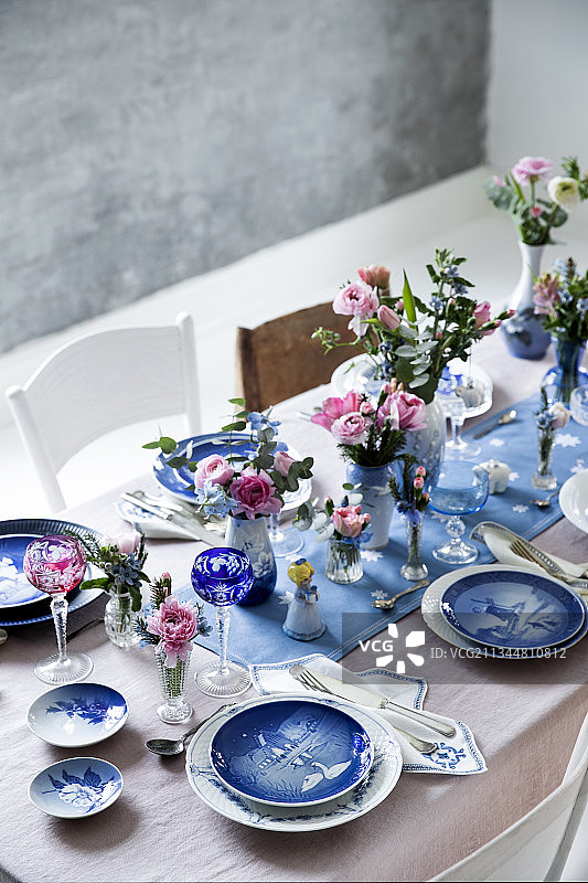 在圣诞餐桌上摆放蓝白餐具和鲜花图片素材