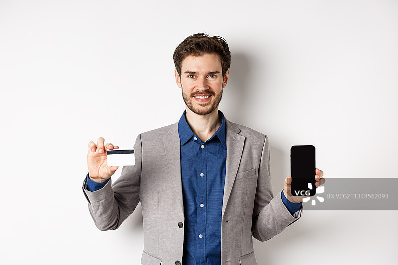 商人手持智能手机站在白色背景下的肖像图片素材