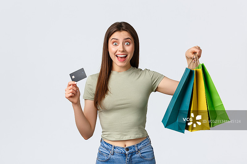 快乐的年轻女人的肖像拿着购物袋和信用卡在白色背景图片素材