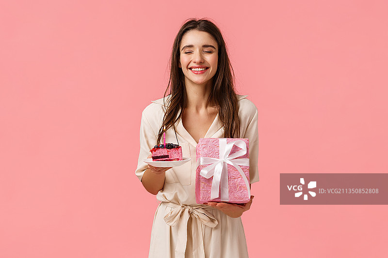 微笑的年轻女子的肖像拿着礼物盒在粉红色的背景图片素材