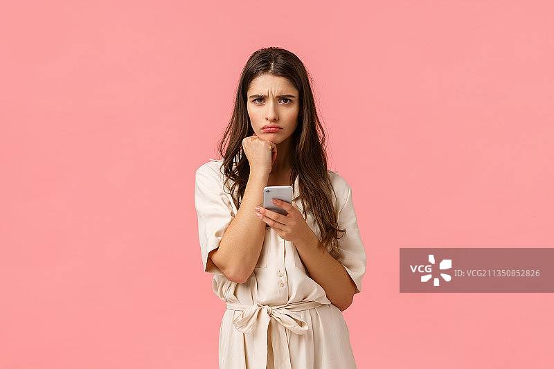 年轻女子的肖像使用手机在粉红色的背景图片素材
