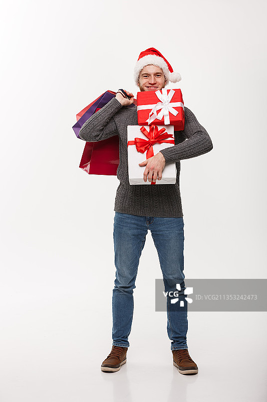 拿着圣诞礼物的年轻人站在白色背景下图片素材