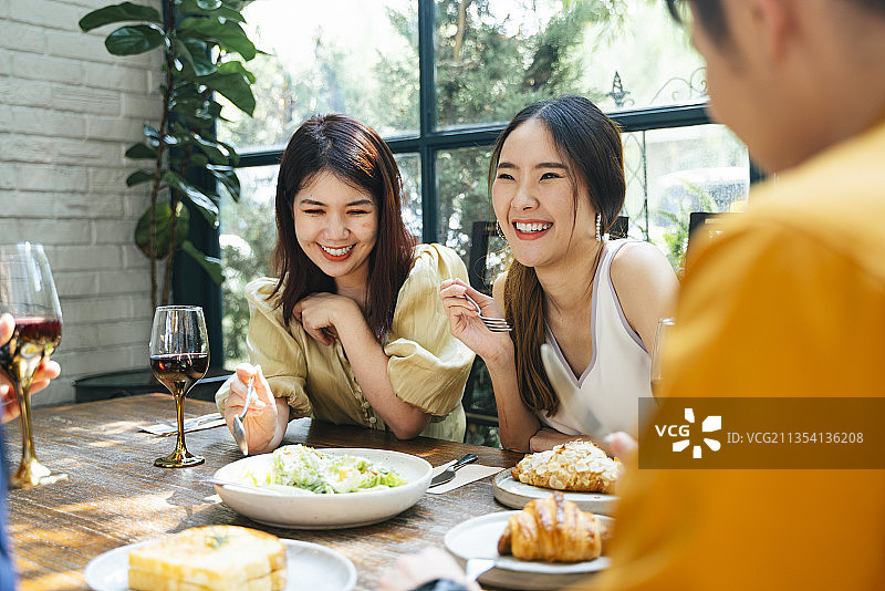 两个开朗的亚洲泰国女人享受与朋友在餐厅吃早午餐。图片素材