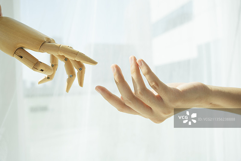 木制机器人的手和人的手相互接触。图片素材