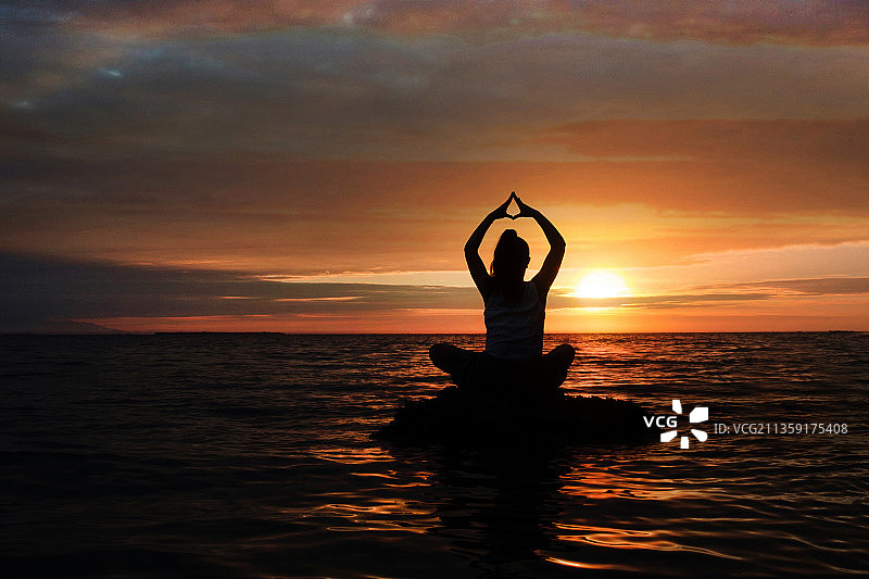 日落时分，菲律宾宿务的班塔延岛，在海上船上做瑜伽的女人剪影图片素材