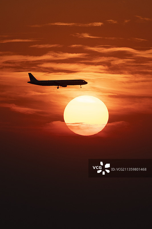 飞机在日落时迎着天空飞行的剪影图片素材
