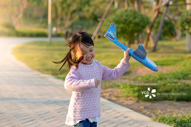 拿着飞机玩具在公园里奔跑的孩子图片素材