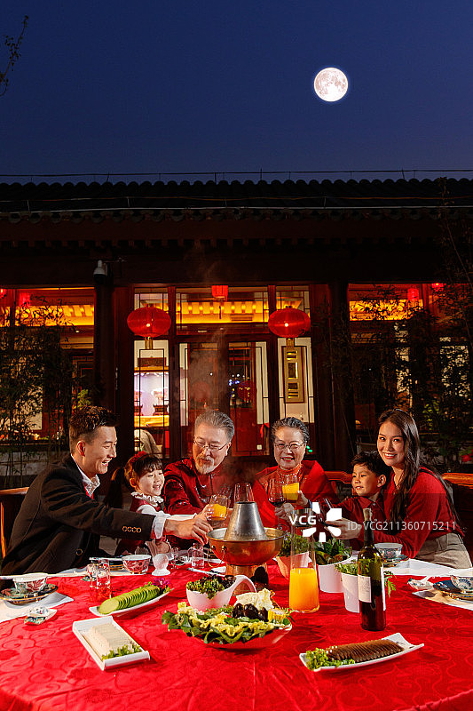 东方家庭在中式庭院内干杯庆祝新年图片素材