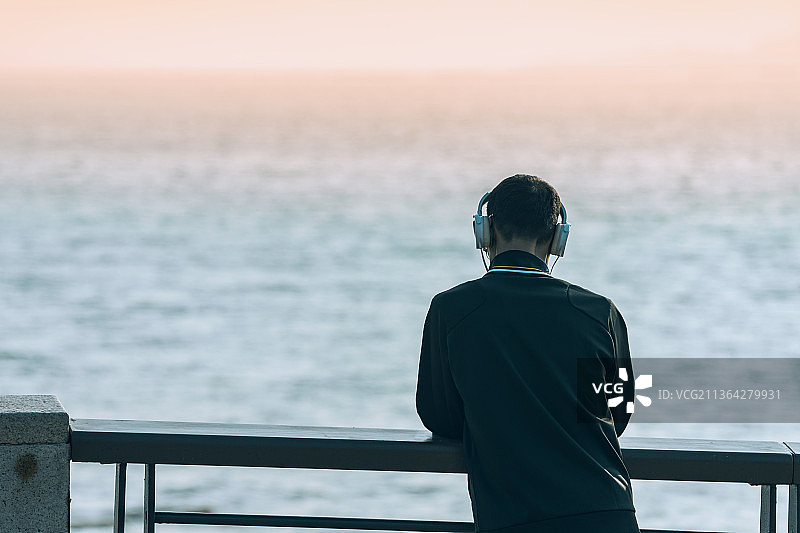 海边带着耳机听音乐的男人背景图片素材