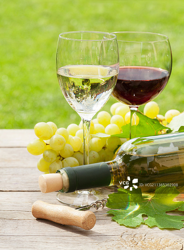 白葡萄酒和红葡萄酒酒杯，以及装有一串葡萄的酒瓶图片素材