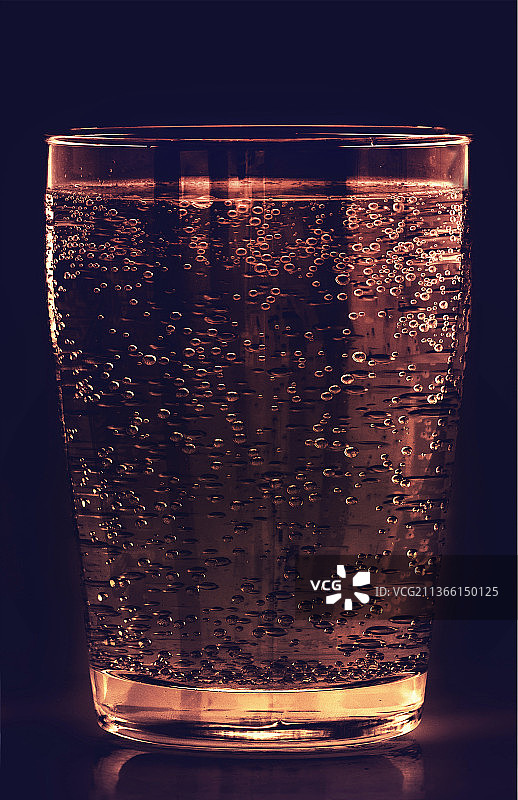 一杯气泡饮料，饮料在桌子上的杯子在黑色背景的特写图片素材