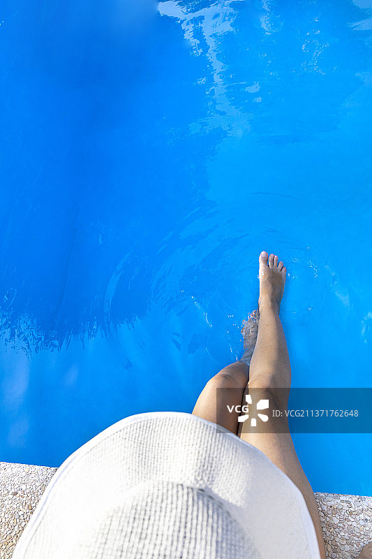 意大利，戴着白色帽子的女子坐在游泳池边图片素材