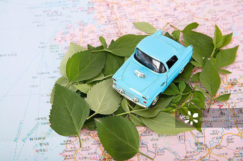 地图上一堆新鲜的树叶和树叶上的小汽车模型图片素材