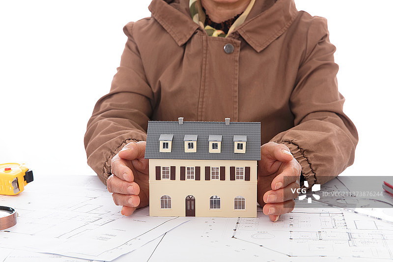 设计师双手呵护着建筑图纸上的小房子模型图片素材