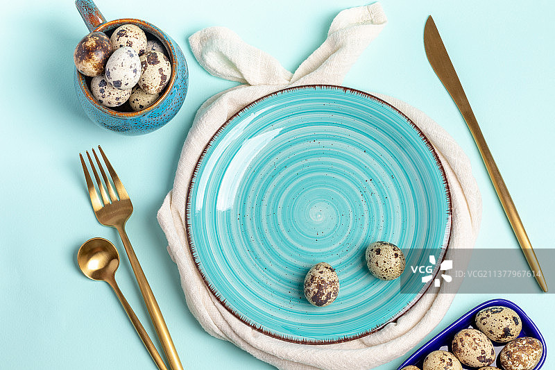 蓝色盘子，金色餐具，鹌鹑蛋在蓝色复活节餐桌设置，俄罗斯图片素材