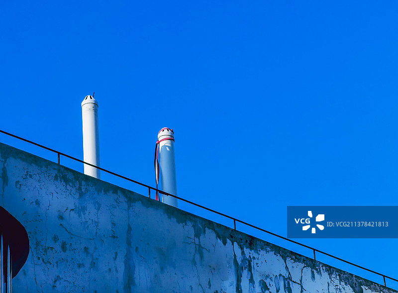蓝色天空背景下居民楼顶的排风管道图片素材