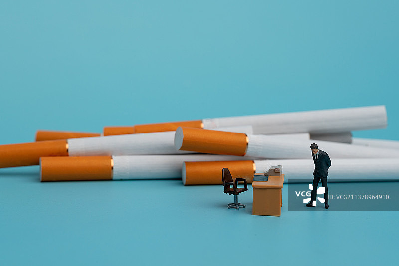 商务男士因烟瘾焦虑的站在办公桌边微缩创意图片素材