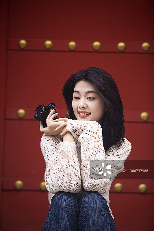 年轻女子在胡同游玩使用数码相机拍照图片素材