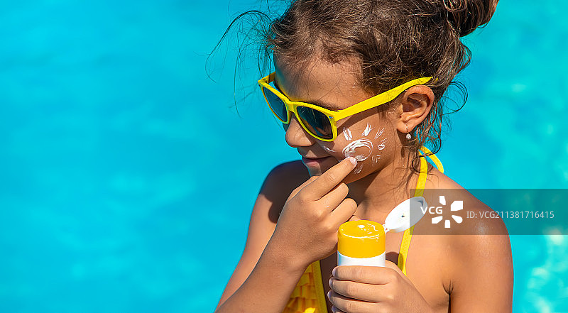 防晒液在泳池附近对孩子的脸进行选择性聚焦图片素材