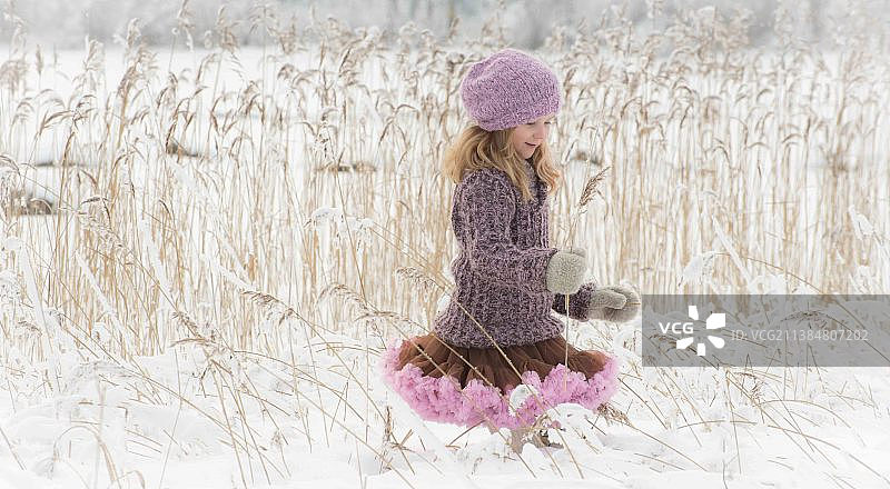享受雪，女孩坐在田野在冬天图片素材