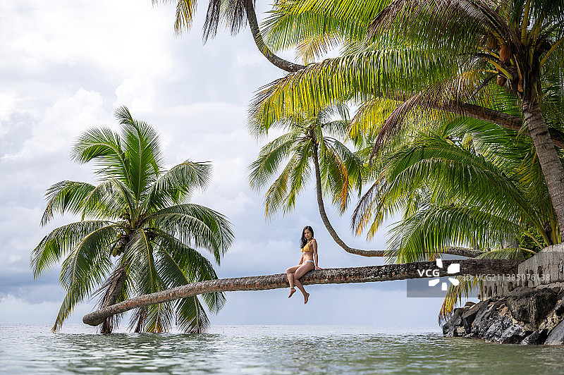 法国波利尼西亚，白天在岛上的热带树木上休息的女人图片素材
