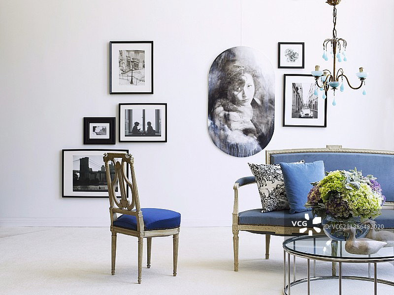 古色古香的沙发与蓝色的装潢和现代的茶几，玻璃顶在墙上的相框照片前面图片素材