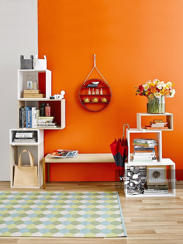 堆叠，立方体货架模块和圆形装饰货架在衣帽间长凳上方的墙壁上，靠在橙色的墙壁上图片素材