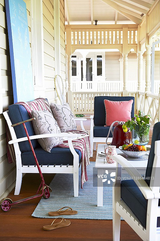 白色的木凳和扶手椅，深蓝色的靠垫围绕着桌子，走廊上有白色的栏杆和旋转的柱子图片素材