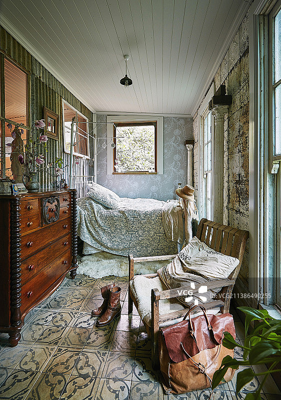 在改造过的马厩里的卧室里，质朴的椅子，古董抽屉柜和床图片素材
