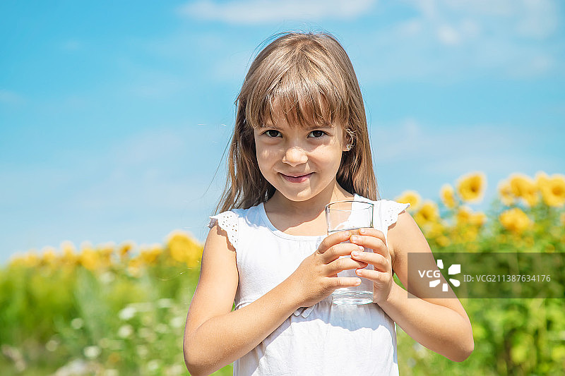 一个孩子正在喝水，背景是田野选择性聚焦图片素材