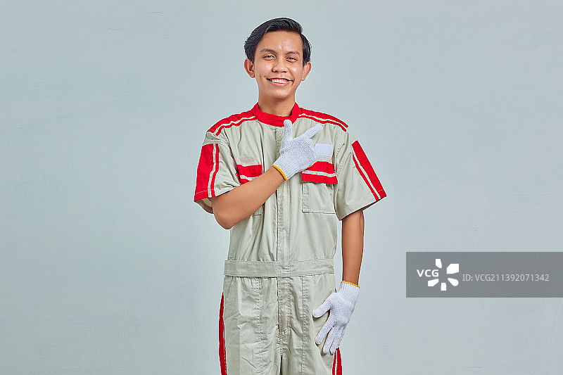 年轻机械师的肖像问候与大微笑在他的脸上孤立的灰色背景，印度尼西亚图片素材