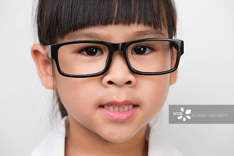 一个带着眼镜微笑的小女孩的肖像在一个医生，泰国图片素材