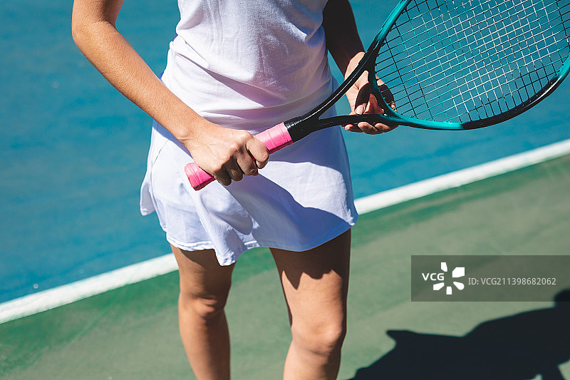 阳光明媚的一天，年轻的白人女性选手在球场上拿着网球拍图片素材
