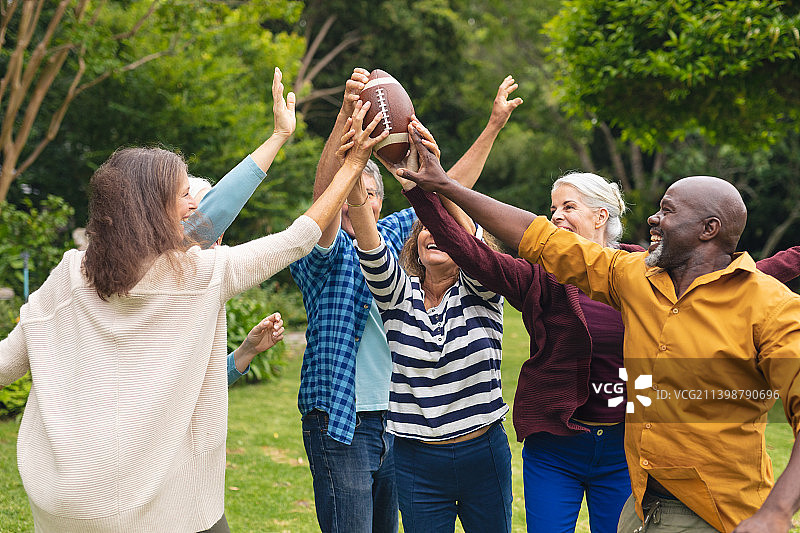 快乐的多种族积极的高级男性和女性朋友拿着橄榄球手举起图片素材