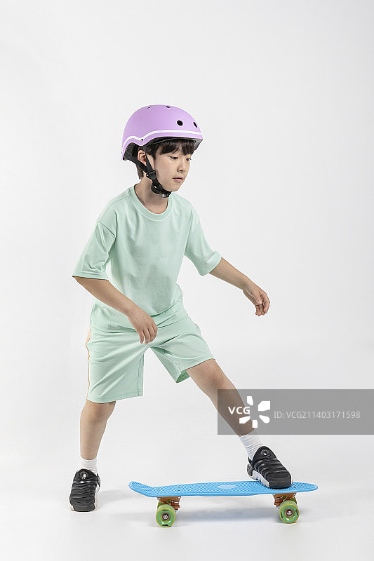 一个穿着运动服的韩国小女孩在白色背景下玩滑板图片素材