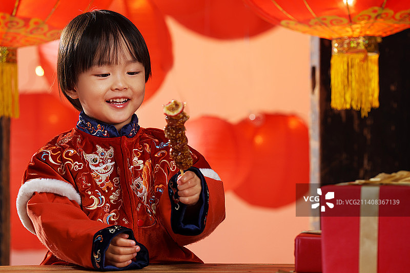 可爱的小男孩拿着糖葫芦庆新年图片素材
