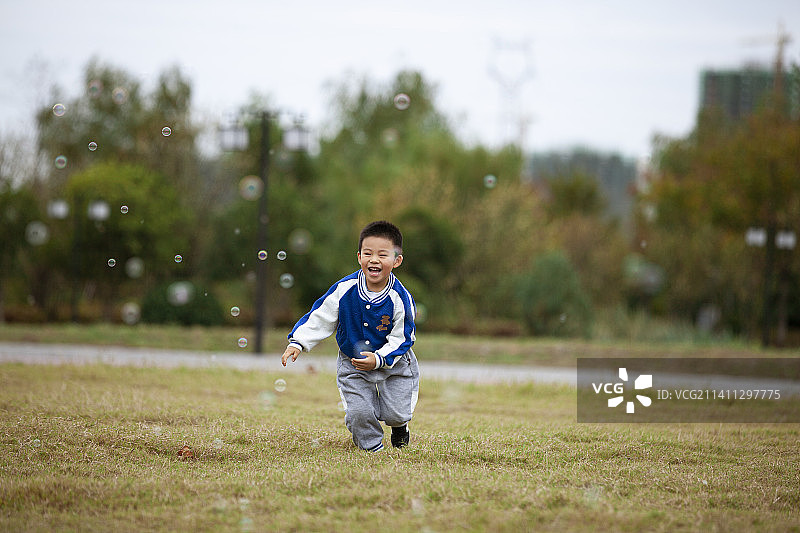 小男孩在草地上追泡泡玩耍图片素材